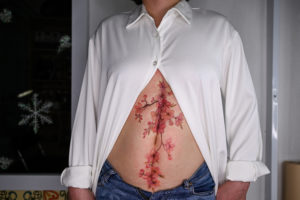 This photograph taken on 31 March 2021 shows a female customer posing with her new tattoo design to cover her stomach scars at tattoo artist Ngoc Like's studio in Hanoi