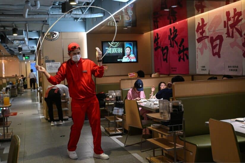 A staff member swings a noodle strand at a Haidilao hot pot restaurant in a shopping mall complex in Beijing.