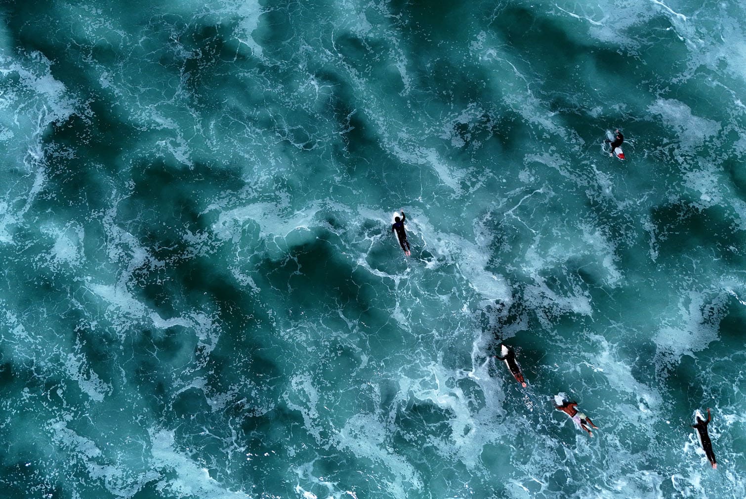 surfers swimming past waves