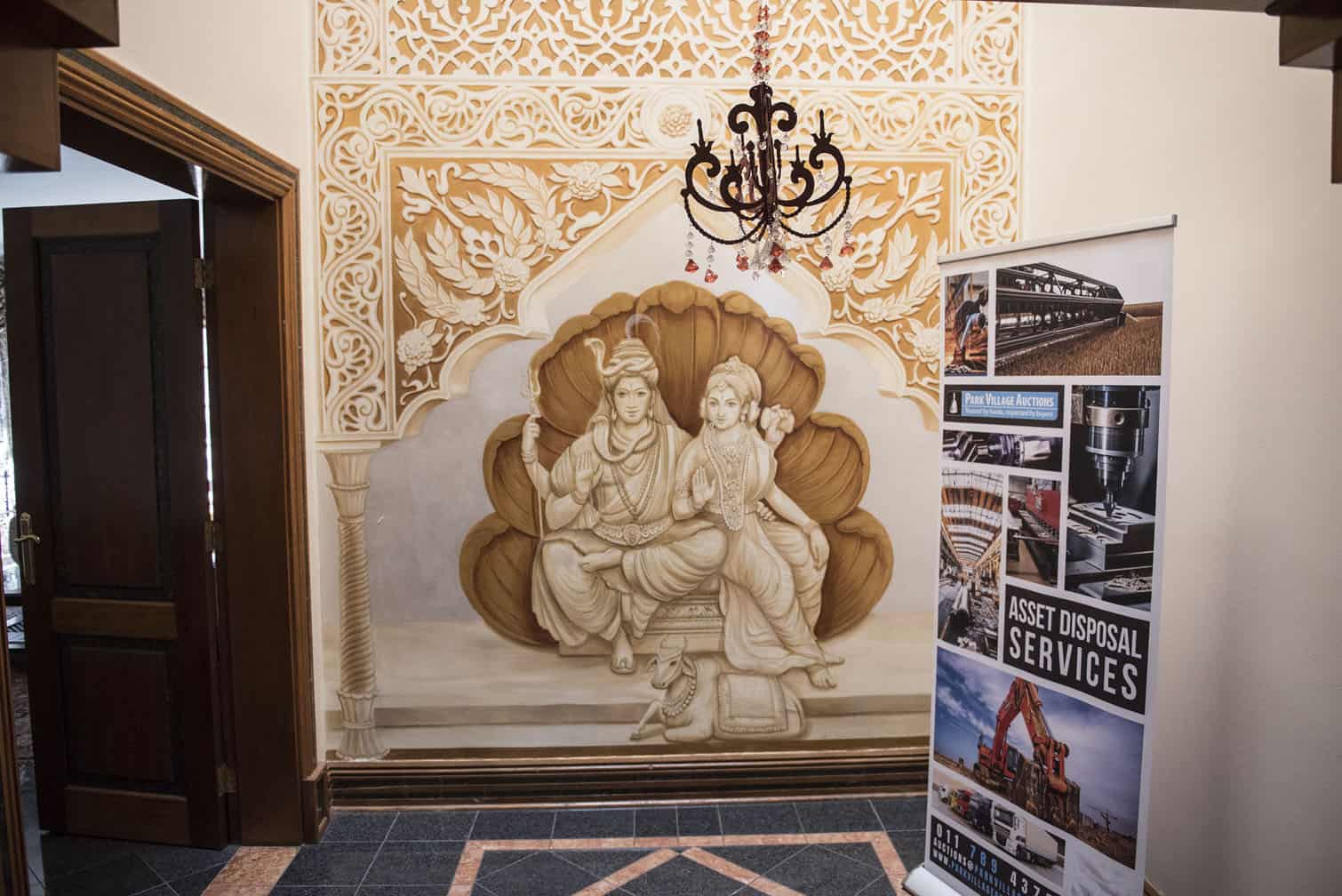 A hallway with a mural of a woman and a chandelier.