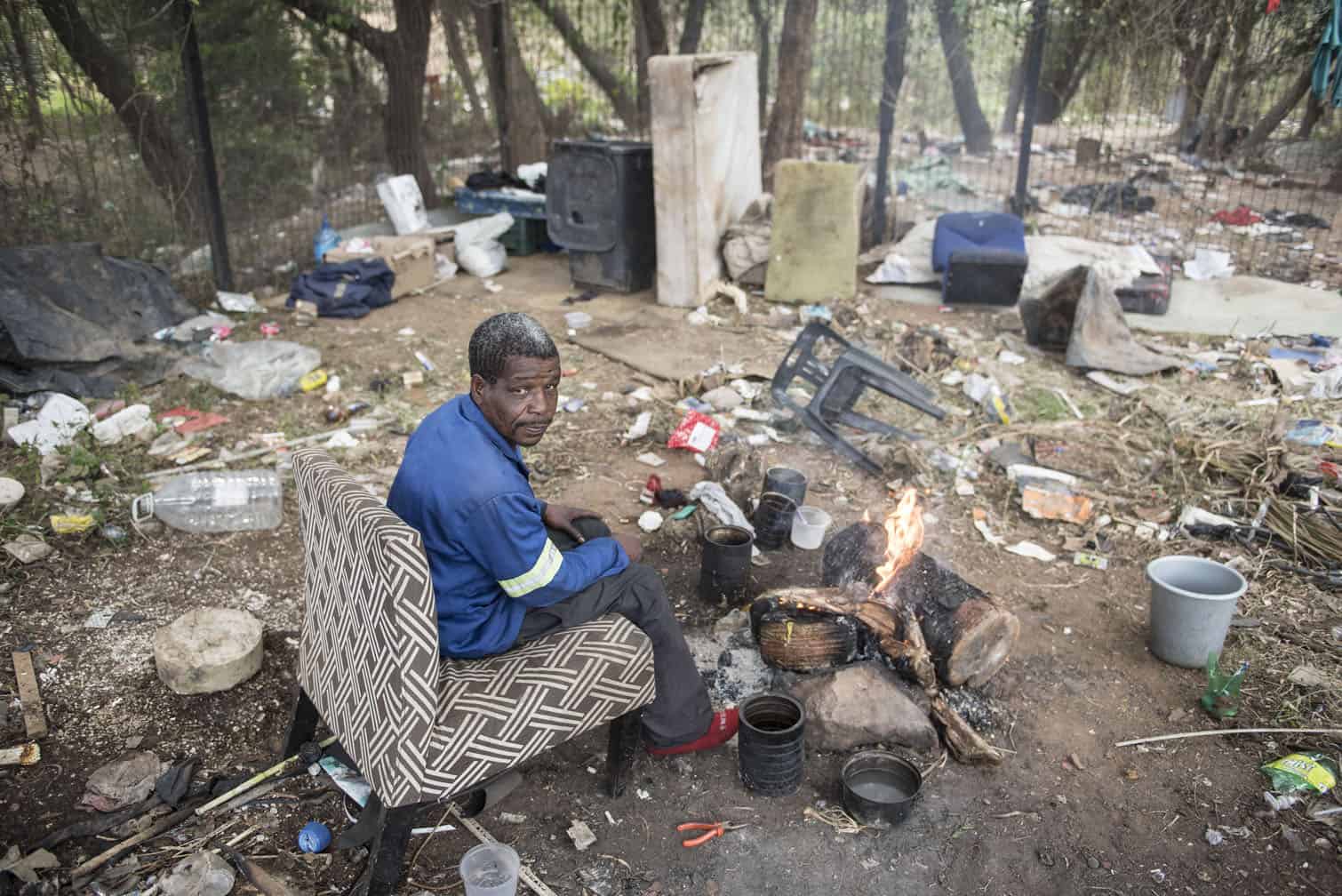 Dennis Manyisa warms himself at a fire after being evicted