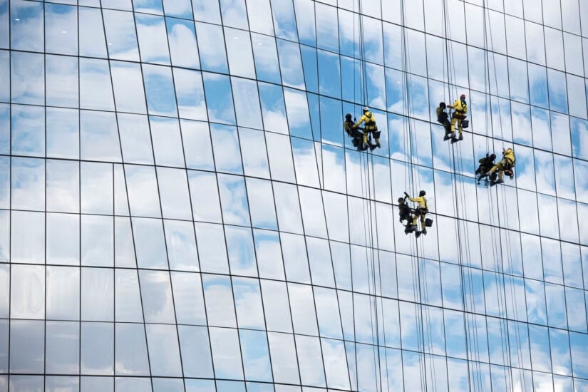 Workers clean the windows of the Anglo American De Beers Group building