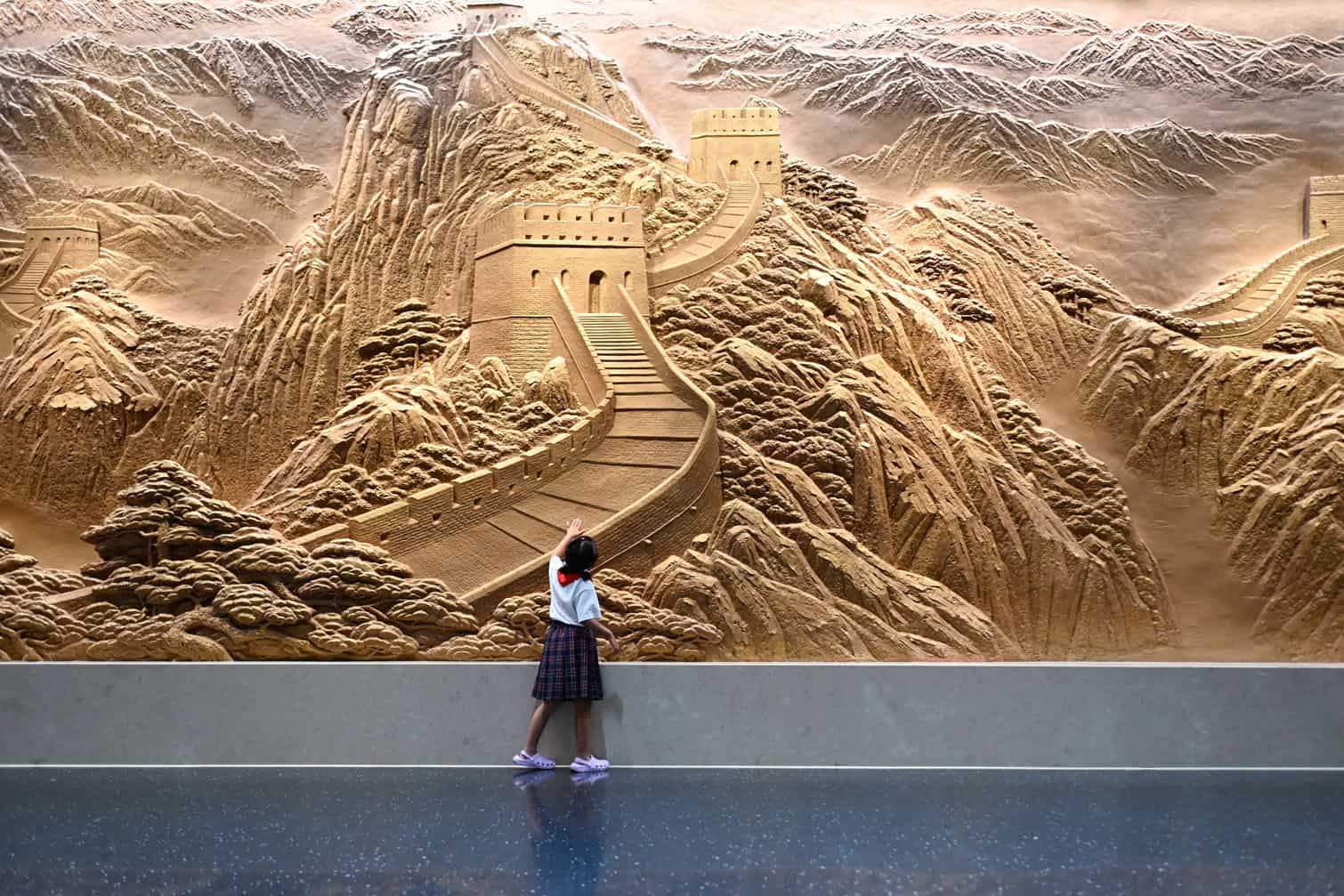 A child looks at a mural of the Great Wall of China