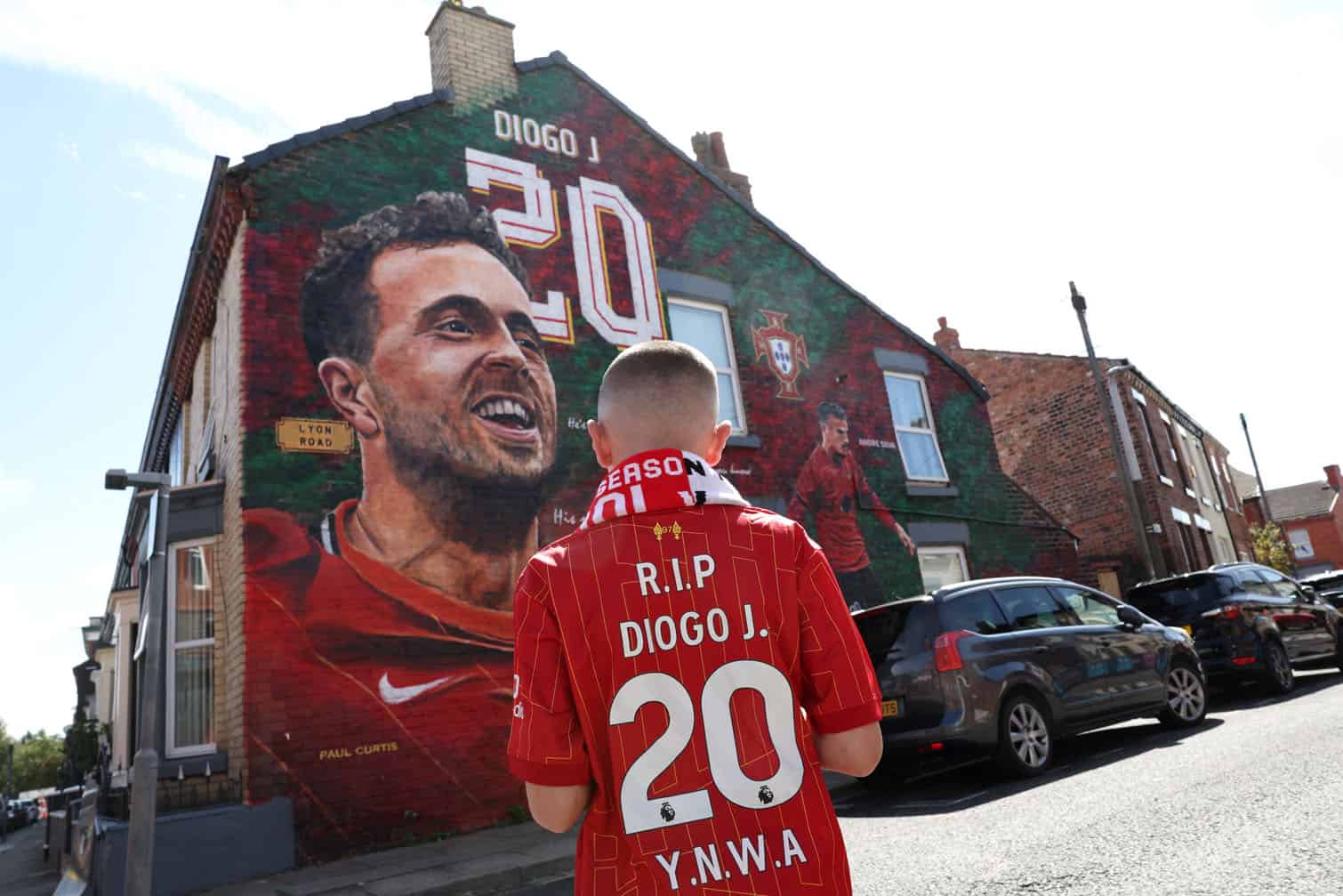 A fan stands in front of a mural by artist Paul Curtis