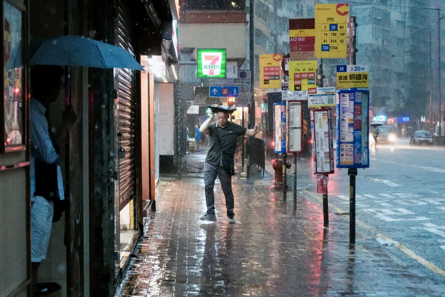 A pedestrian holds a bag over his head