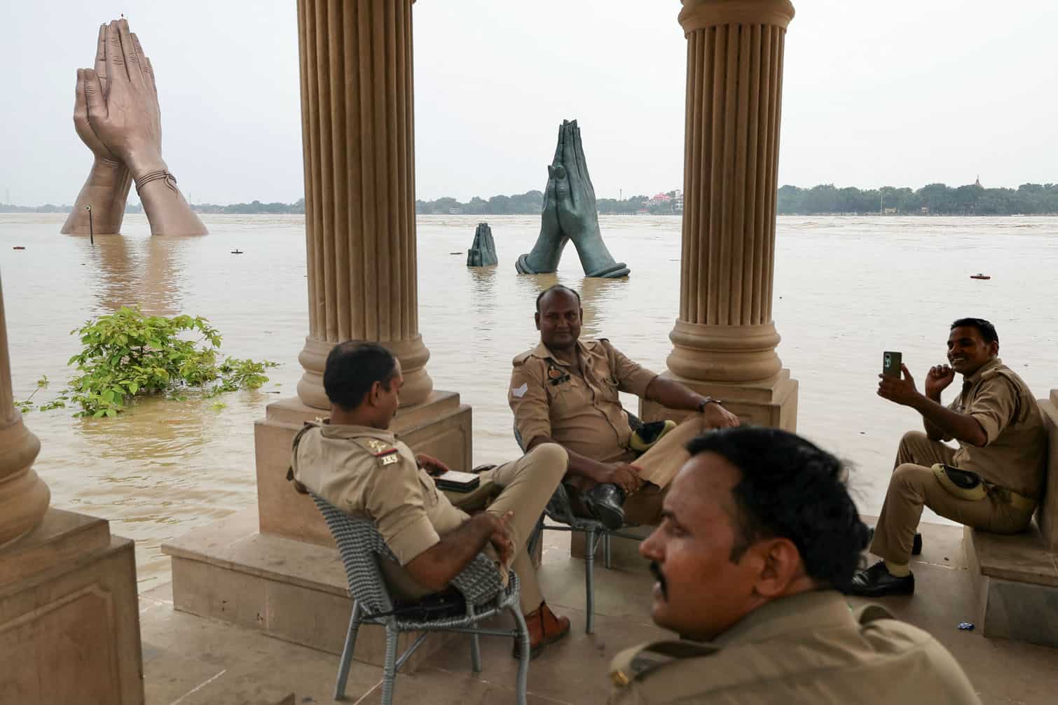 Police personnel sit at the flooded Namo ghat