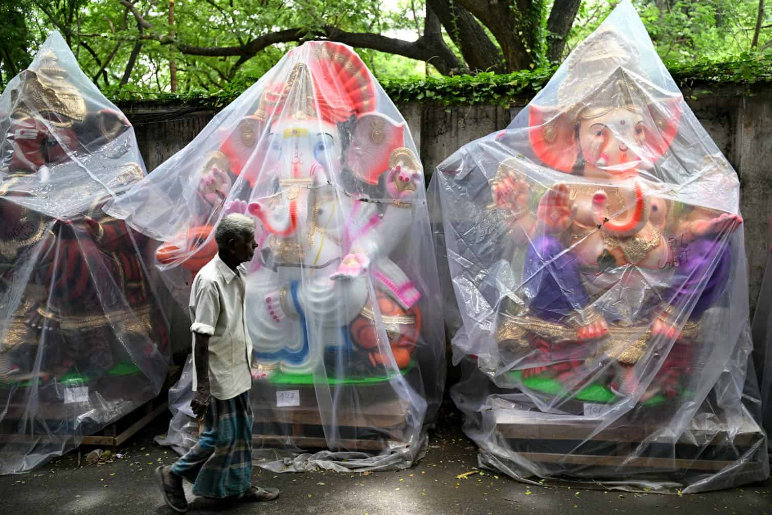 A pedestrian walks past wrapped idols