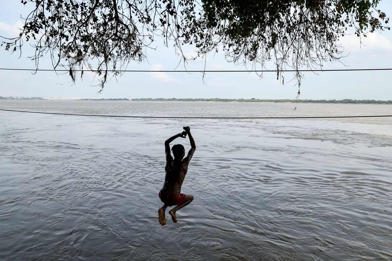 A boy jumps into the flooded Dandi Ghat