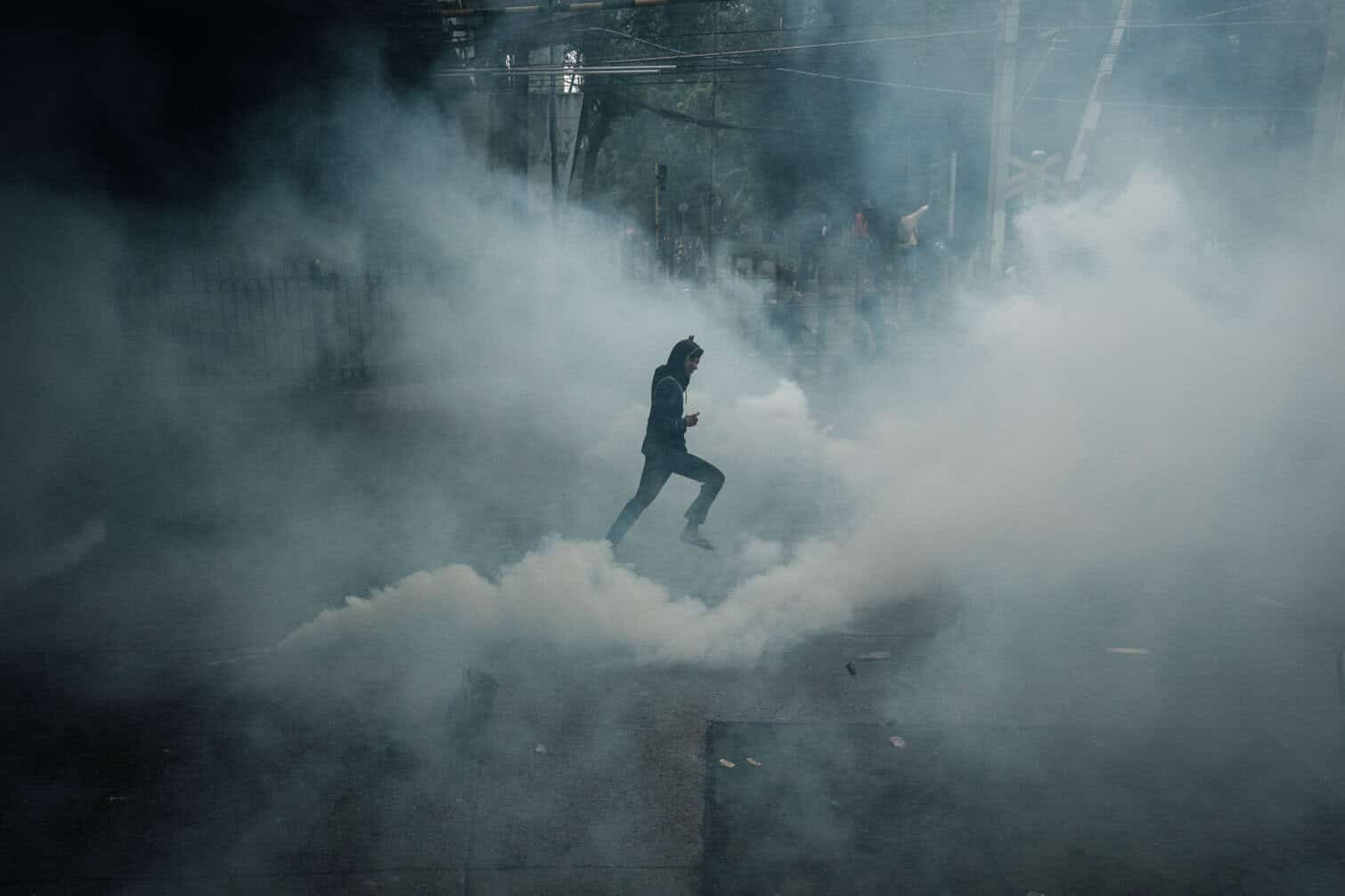 A demonstrator runs through teargas