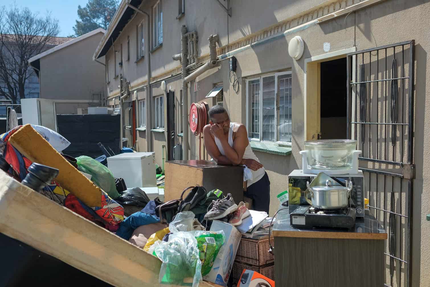 A resident stands with his belongings after being evicted