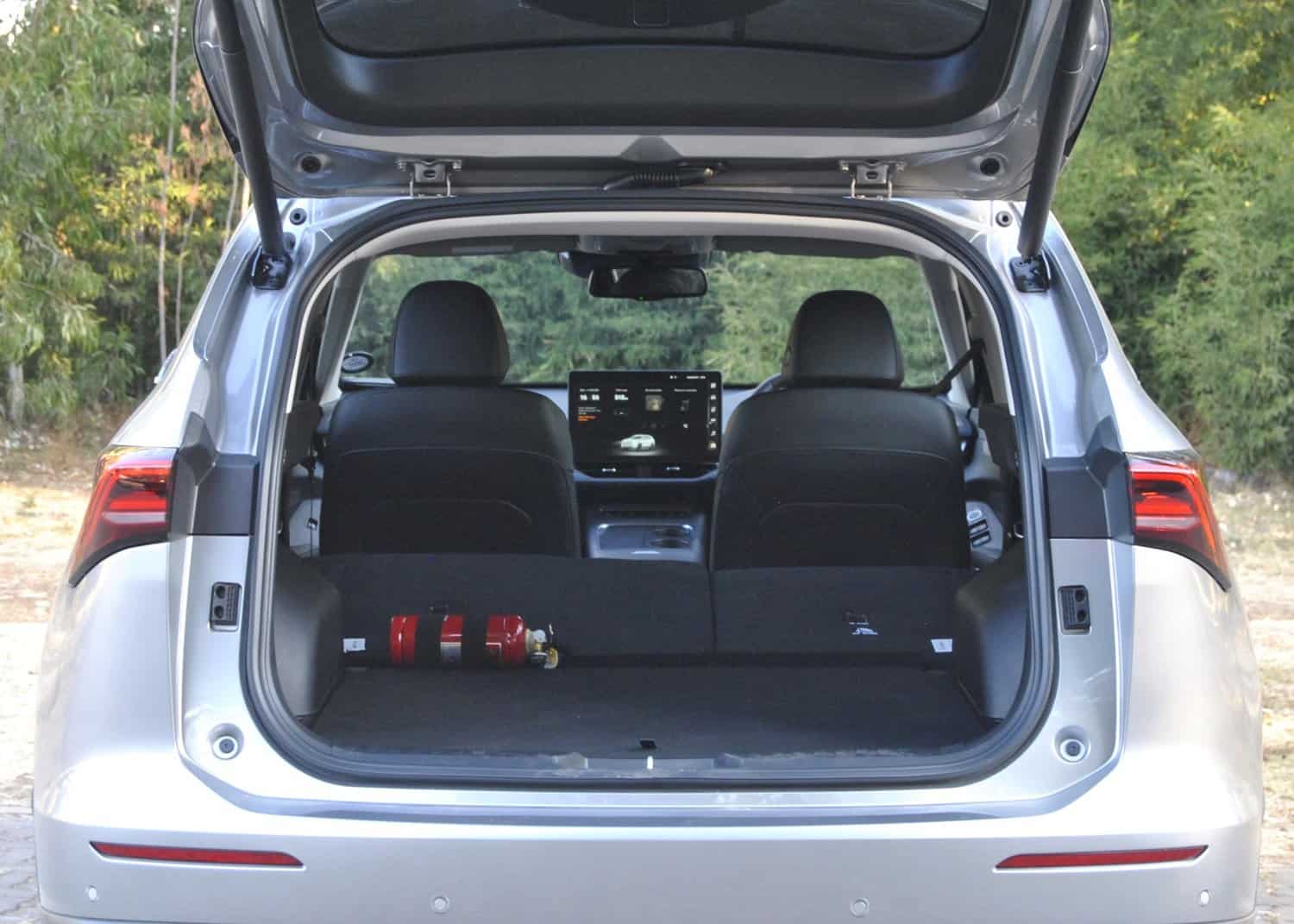 Fire extinguisher in the rear cargo area of a silver SUV with open trunk, outdoors.