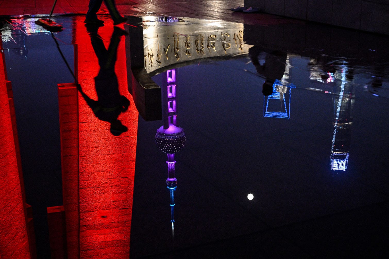 The reflection of people is seen on the water on the Bund promenade