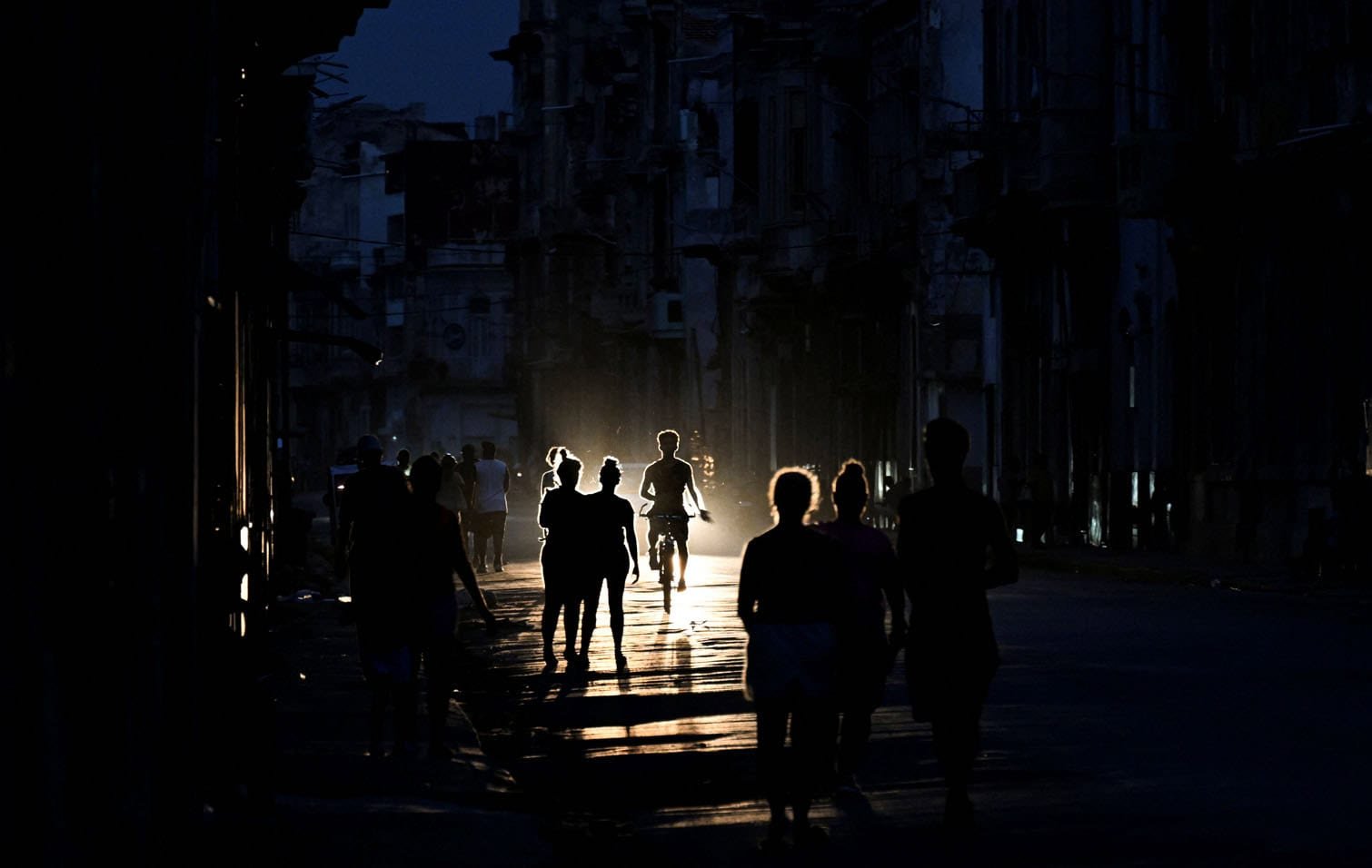 Cubans walk on a street during a blackout