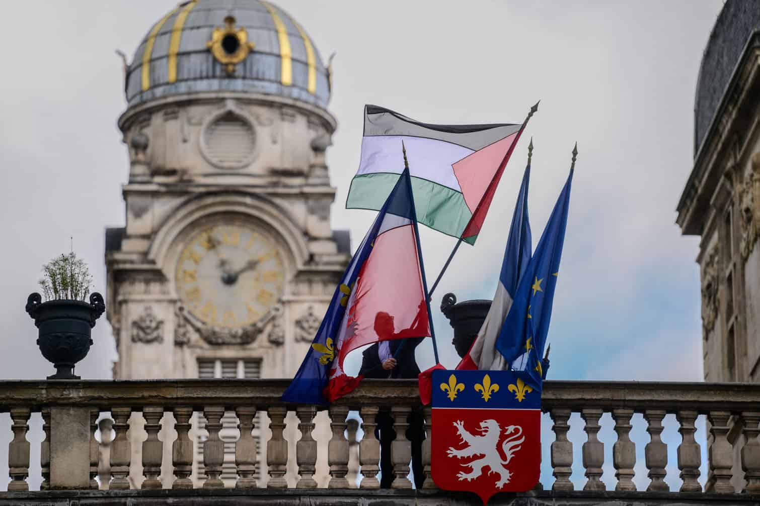 An employee places the Palestinian flag along side the French Flag