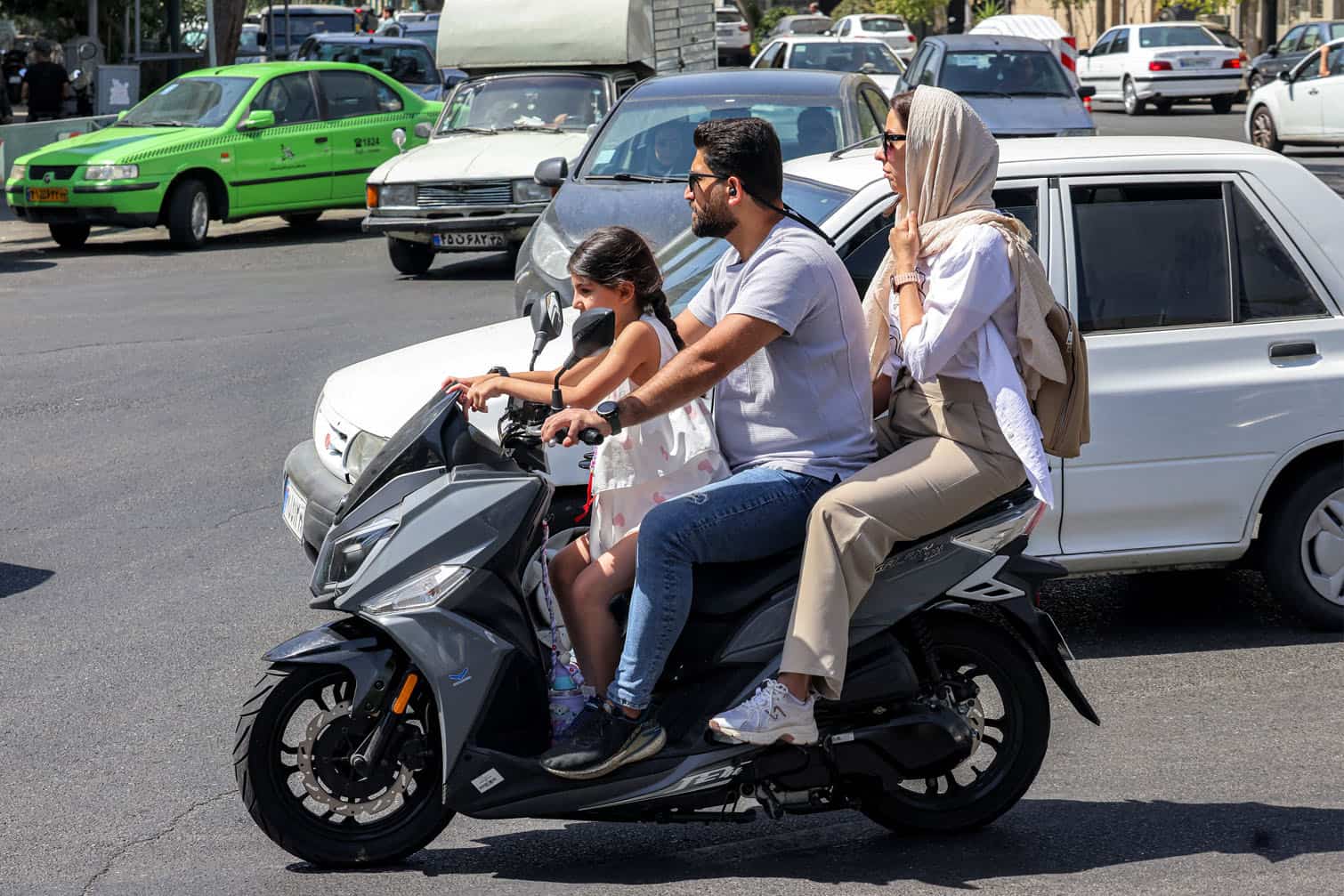 A family of three rides a scooter
