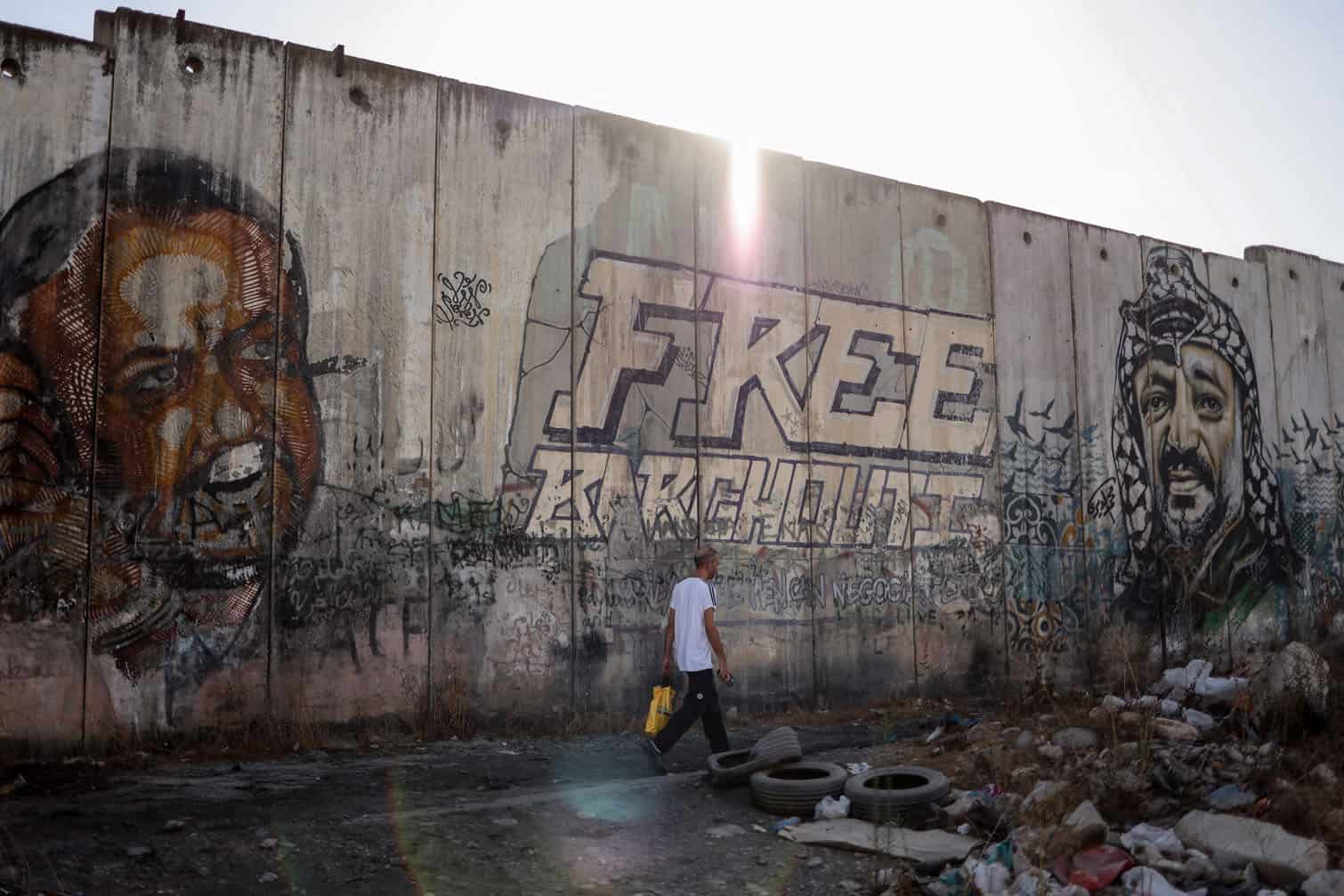 A man walks past portraits of leading member of the Fatah party