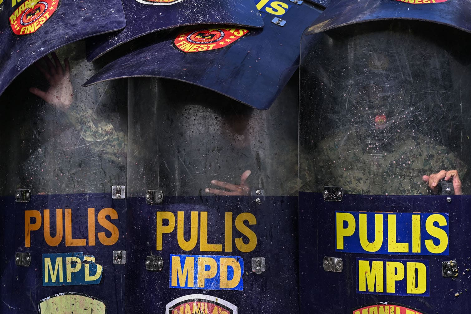 Police protect themselves as protesters throw balloons filled with dirty water