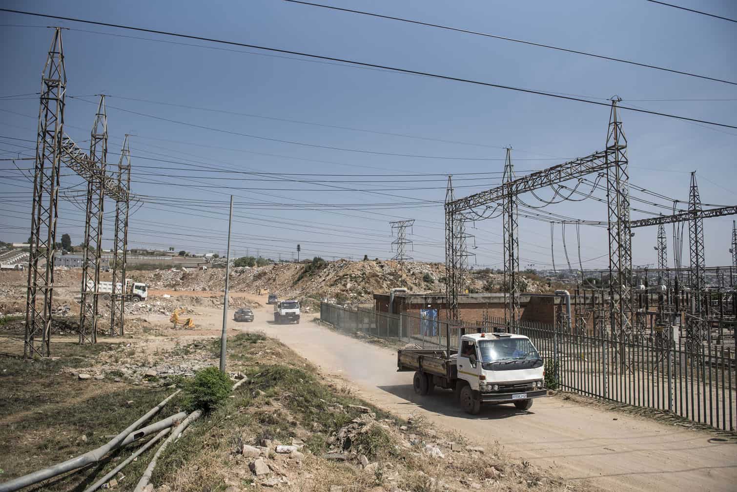 Dumping trucks leave an illegal dumping site in Alexandra