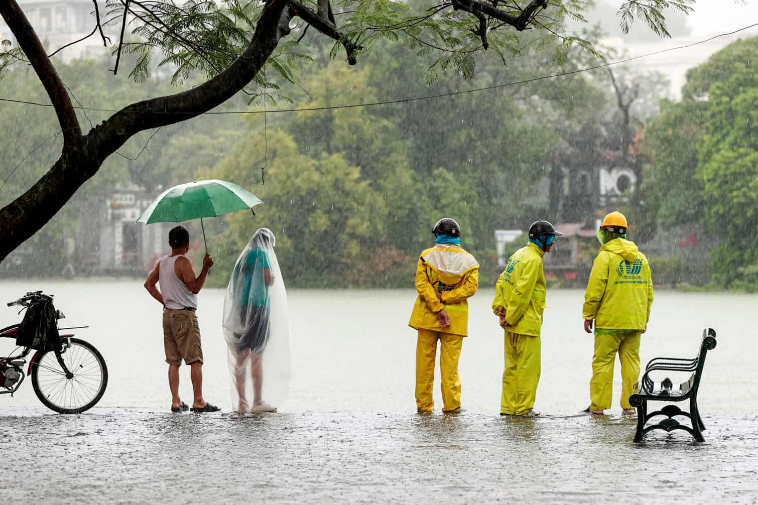 Drainage workers stand next to the overflooding Hoan Kiem Lake