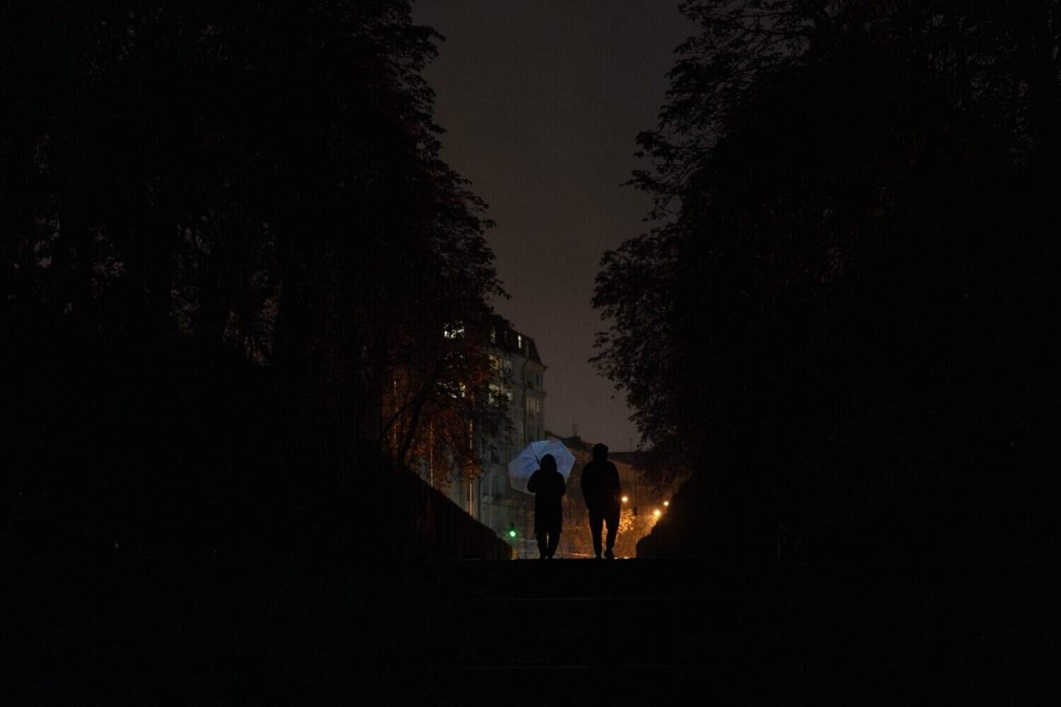 People walk down the street with umbrellas during a power outage in Kyiv on October 10, 2025, following a Russian missiles and drones attacks.