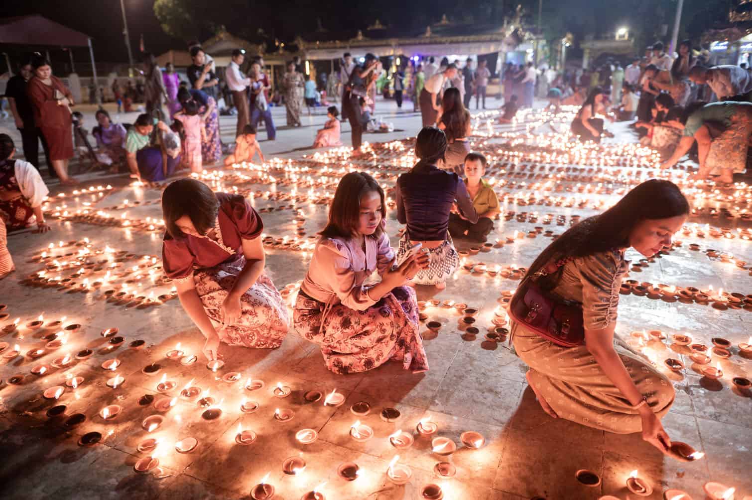 Buddhist devotees light earthern lamps