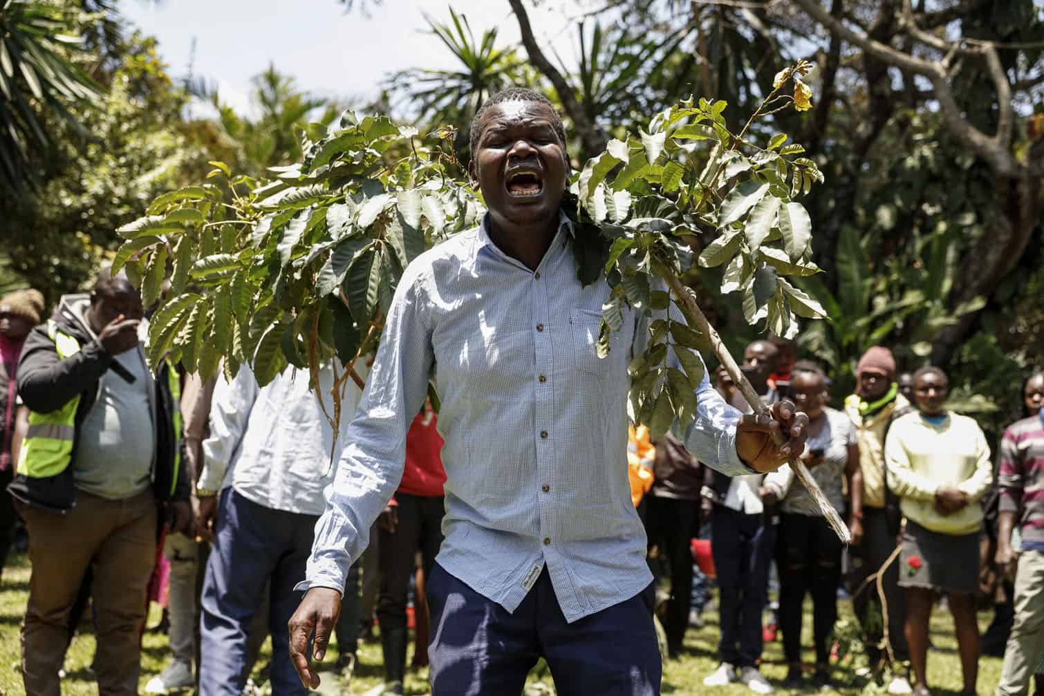A mourner holds a tree branch