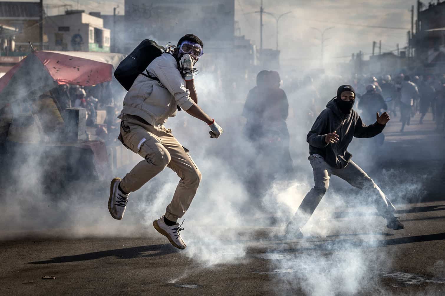 A protester jumps to avoid a teargas canister