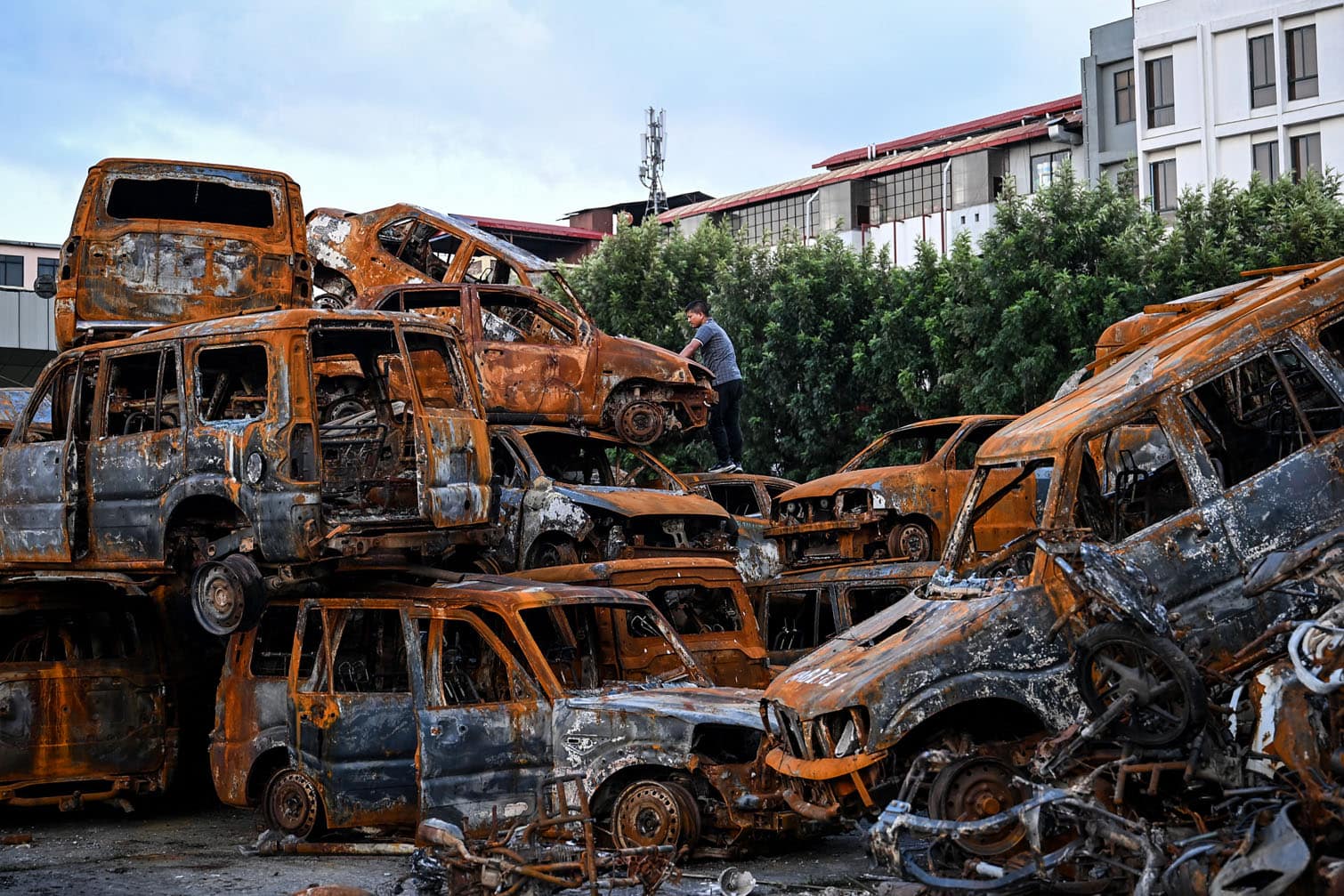 A man looks at charred vehicles