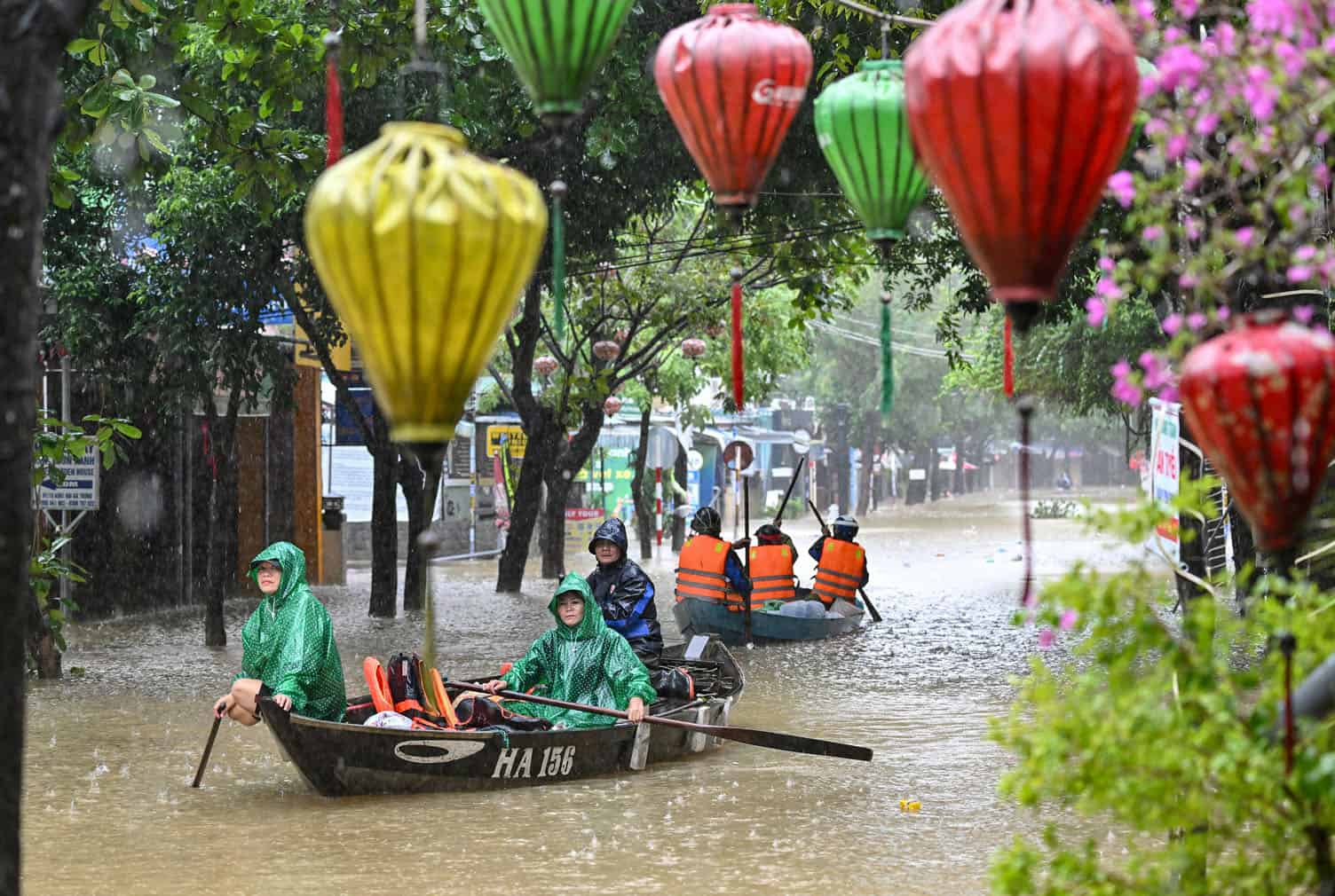 People navigate a flooded street on boats