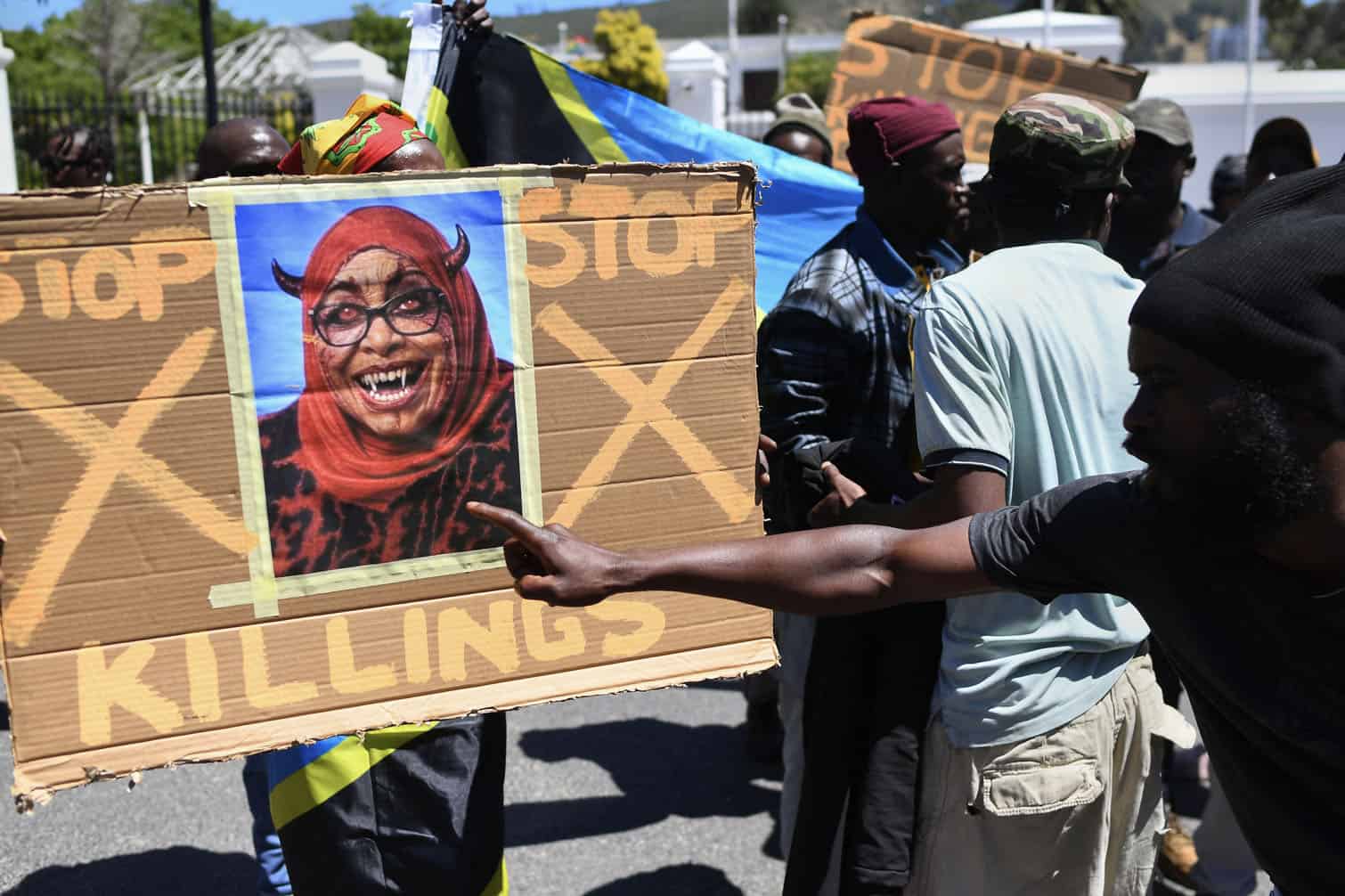 Protesters hold a placard with a picture of the augmented face of Tanzanian President