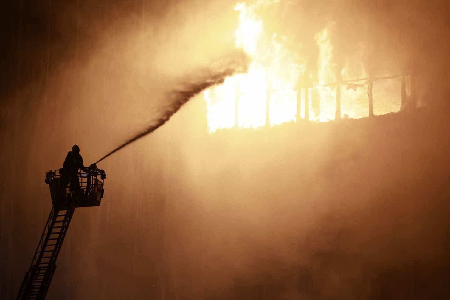 A firefighter uses a water hose as they work to extinguish a blaze