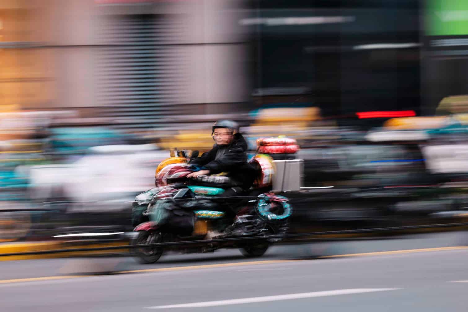 A delivery worker rides on the scooter