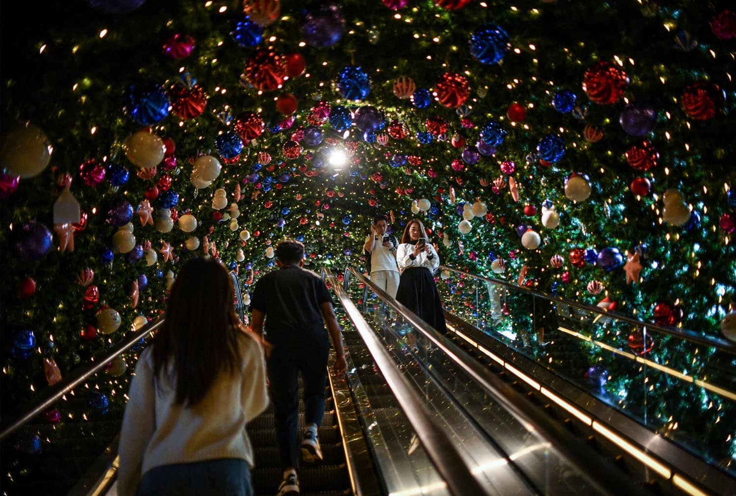 People ride an escalator past Christmas decorations