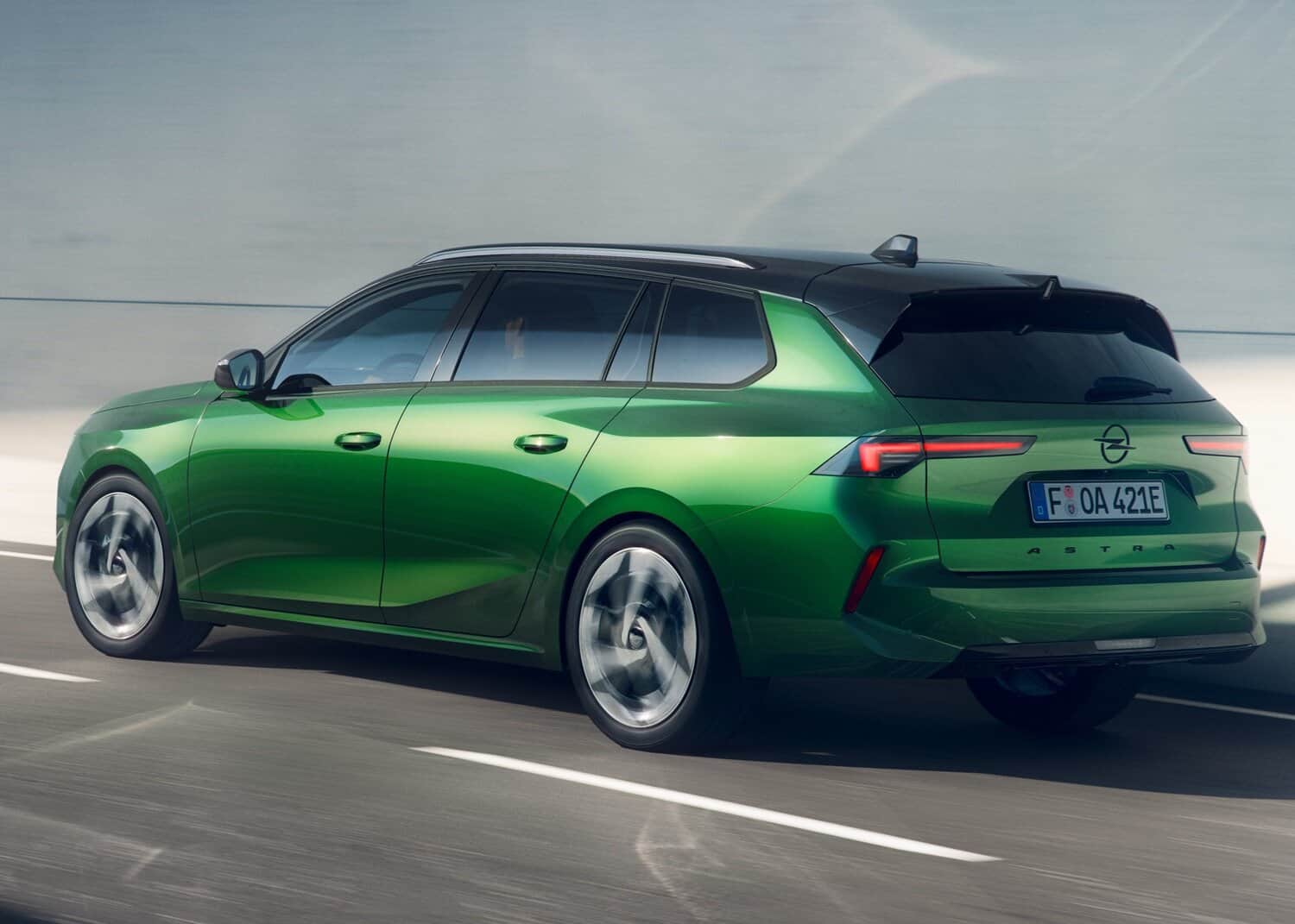Image of a green Opel Astra station wagon driving on the road, emphasizing eco-friendly features and modern design.