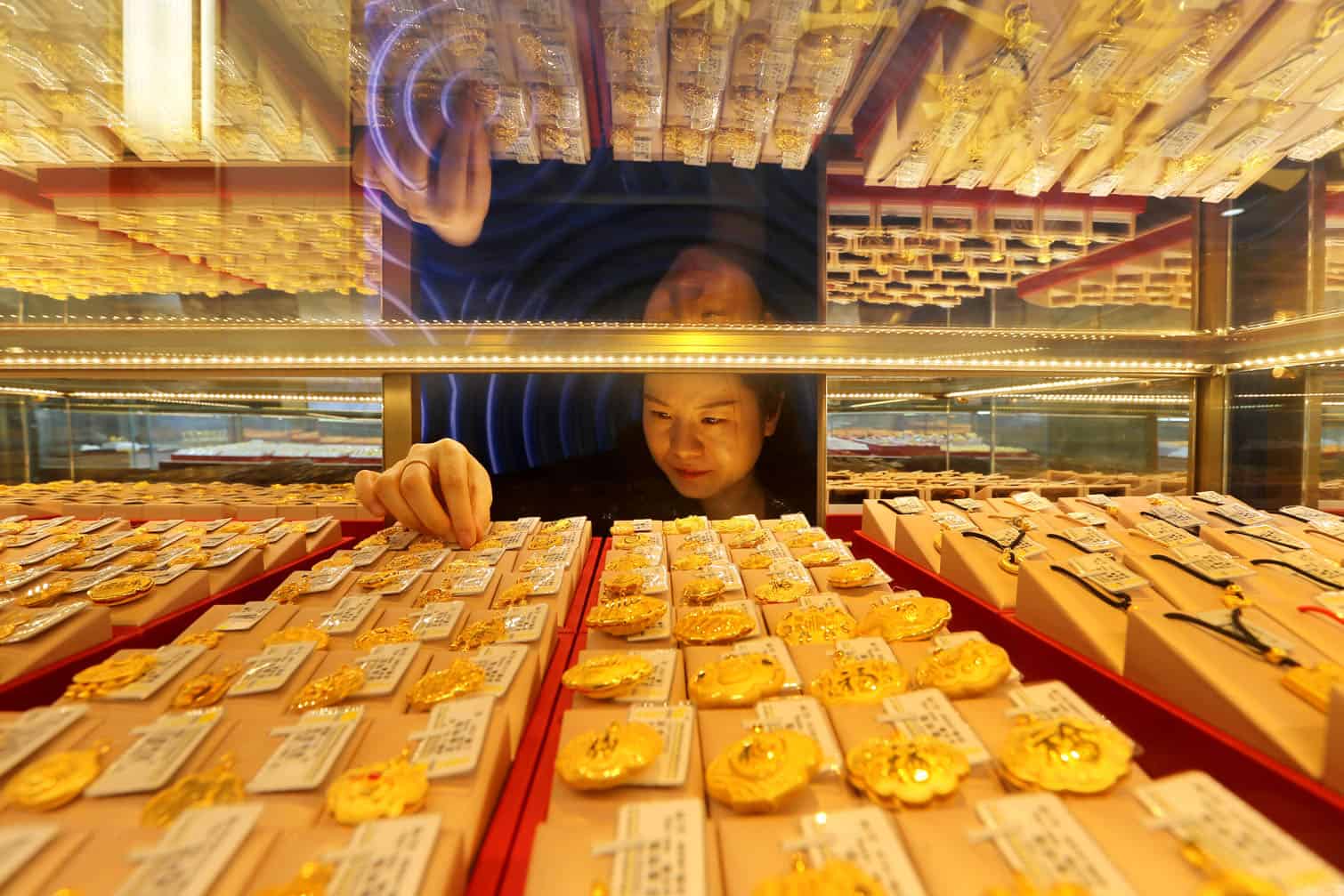 A saleswoman adjusts gold jewellery