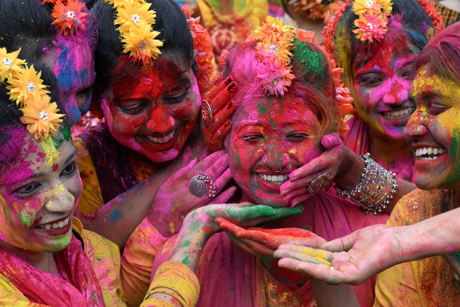 Girls are smeared with coloured powder during Holi celebrations
