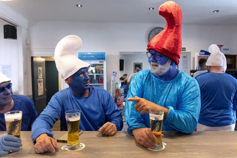 Participants wearing smurf (schtroumpf) costumes share a beer
