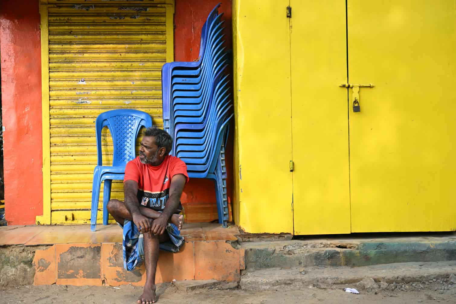 A man sits in front of closed shops in Chennai