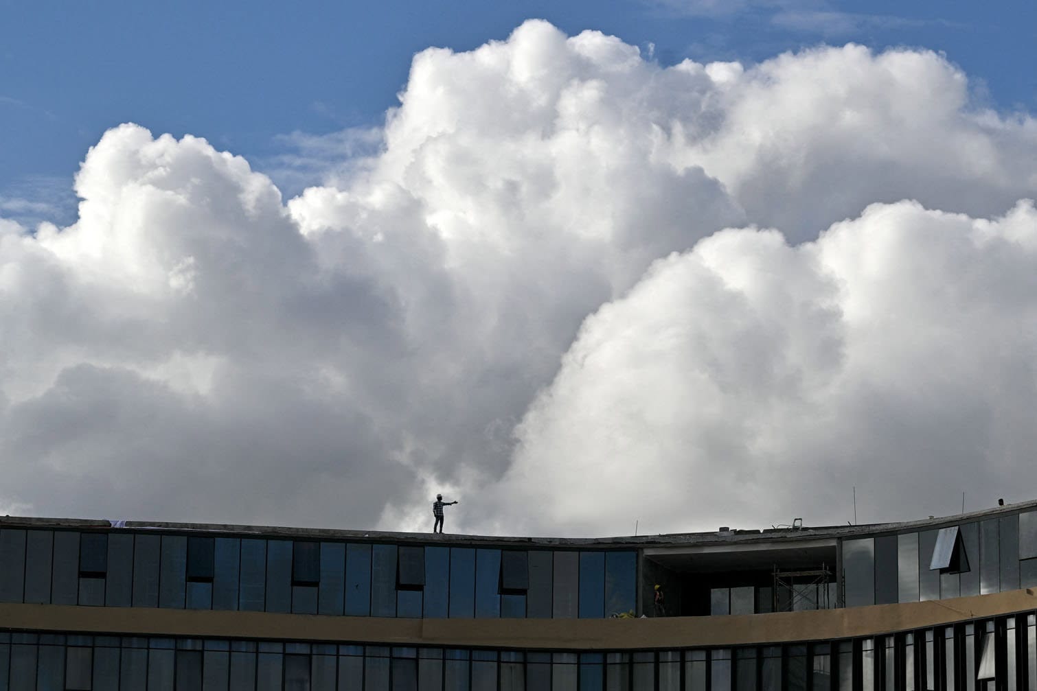 A labourer stands atop an under-construction building
