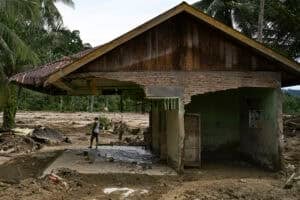 A villager looks around the area from his damaged house after a flash flood
