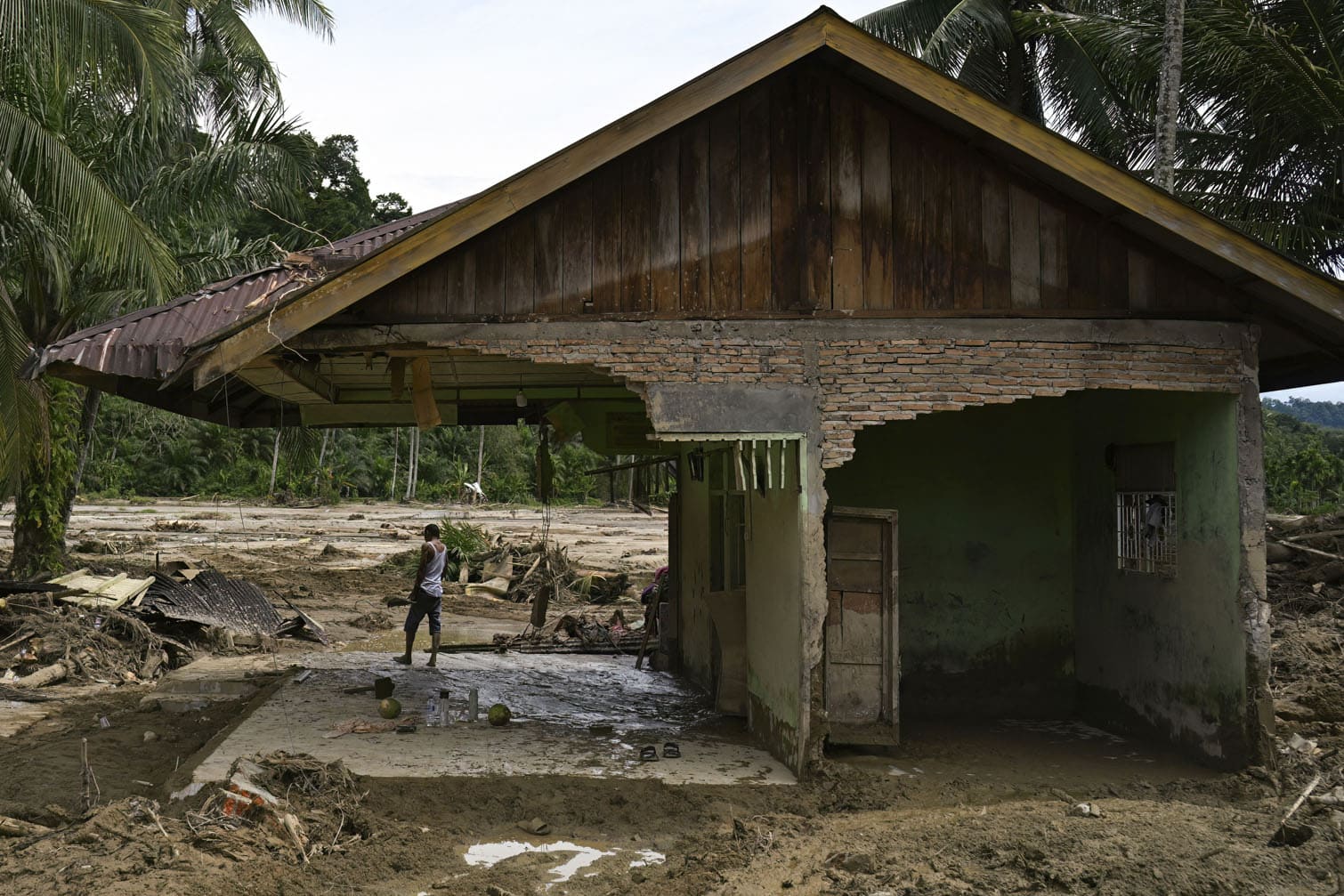 A villager looks around the area from his damaged house after a flash flood