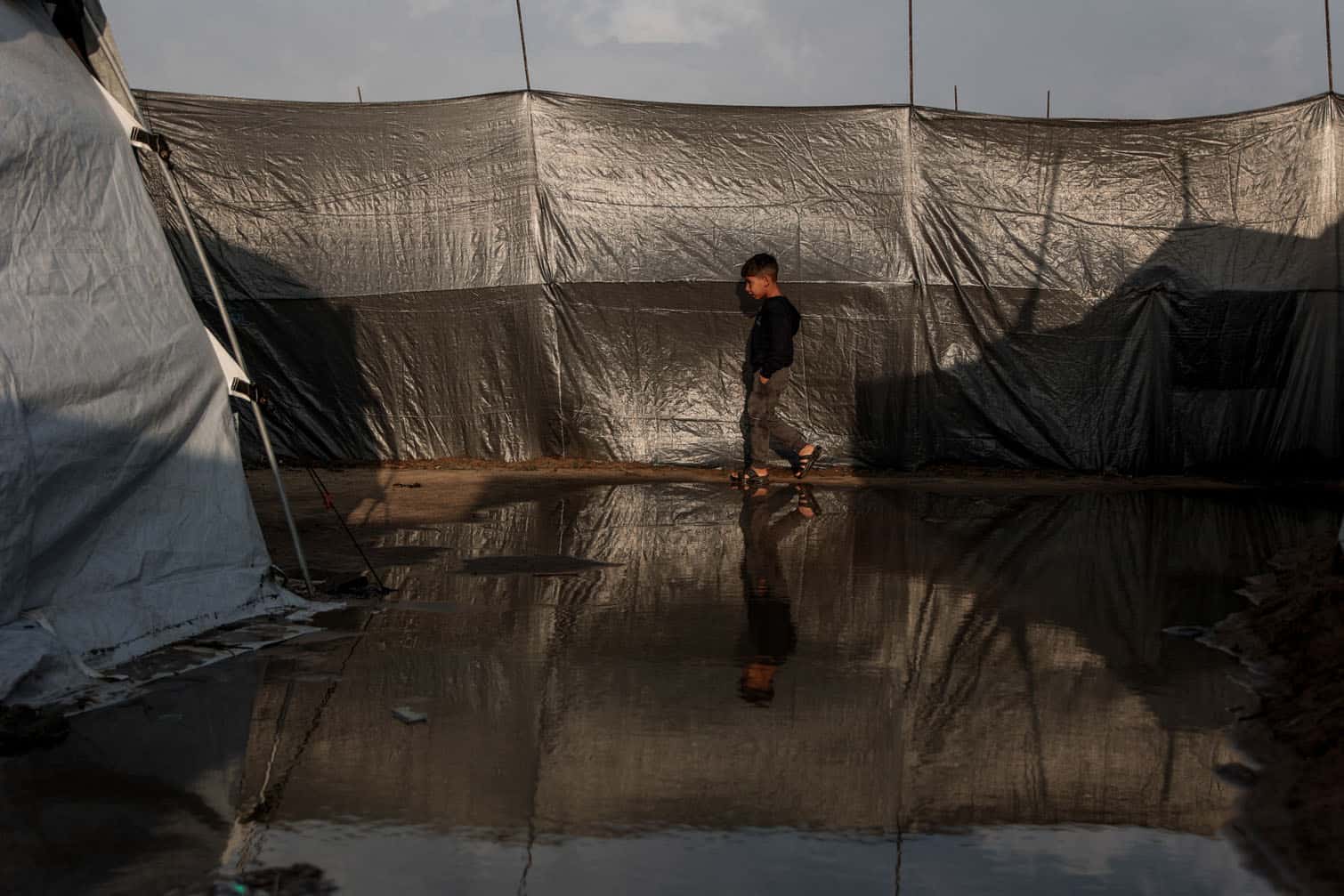 A boy walks through a waterlogged alley
