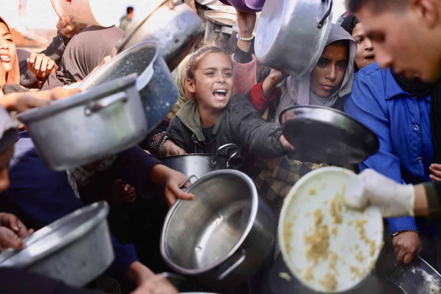 Displaced Palestinians gather to receive donated food