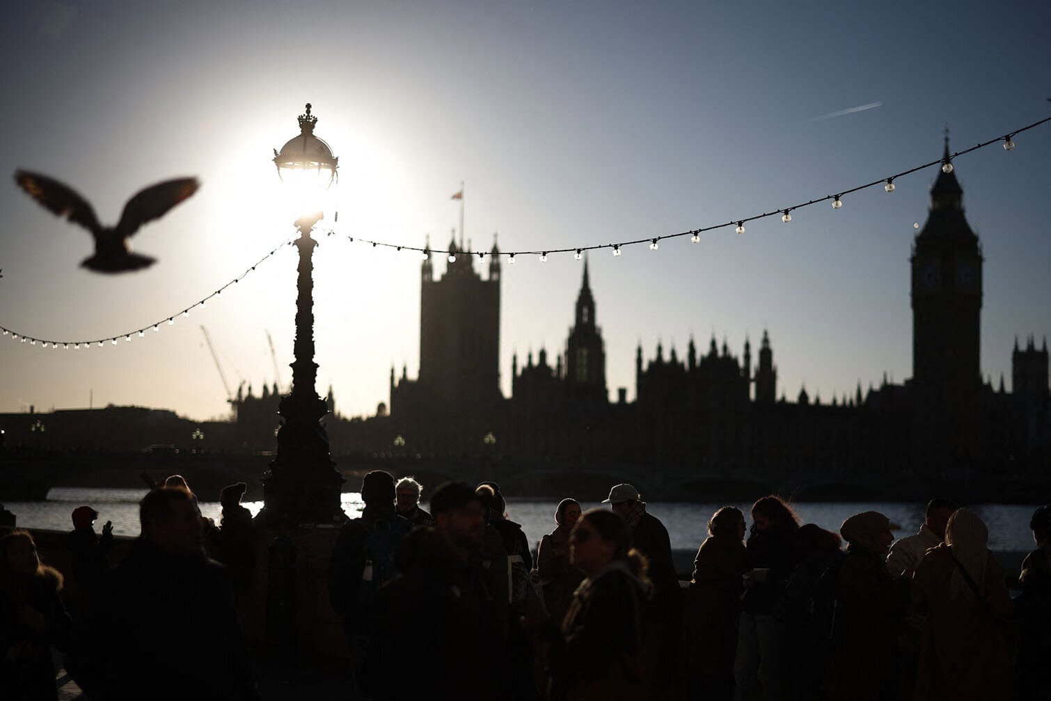 People walk on the south bank with the Palace of Westminster