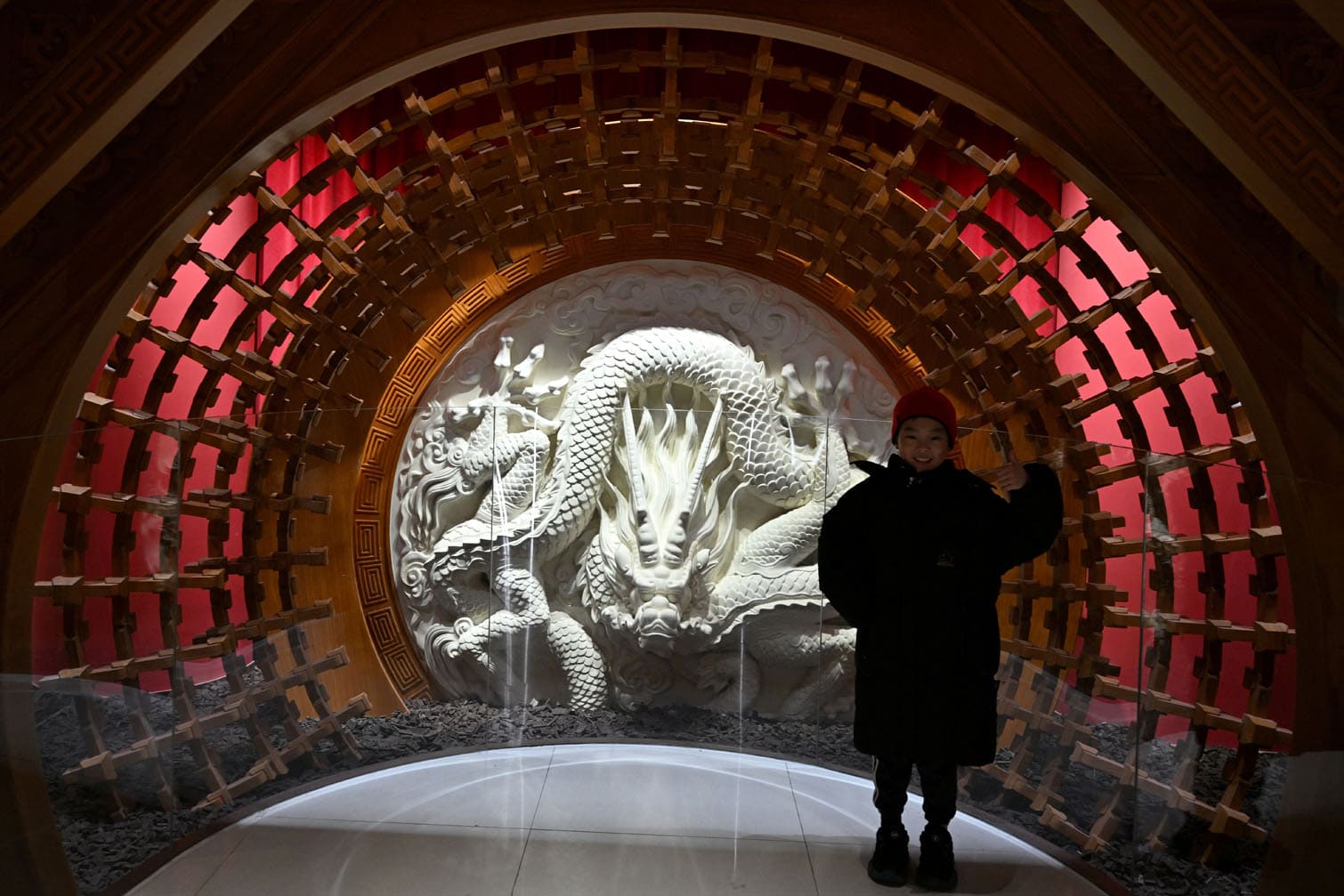 A young visitor poses beside a white dragon exhibit made out of chocolate