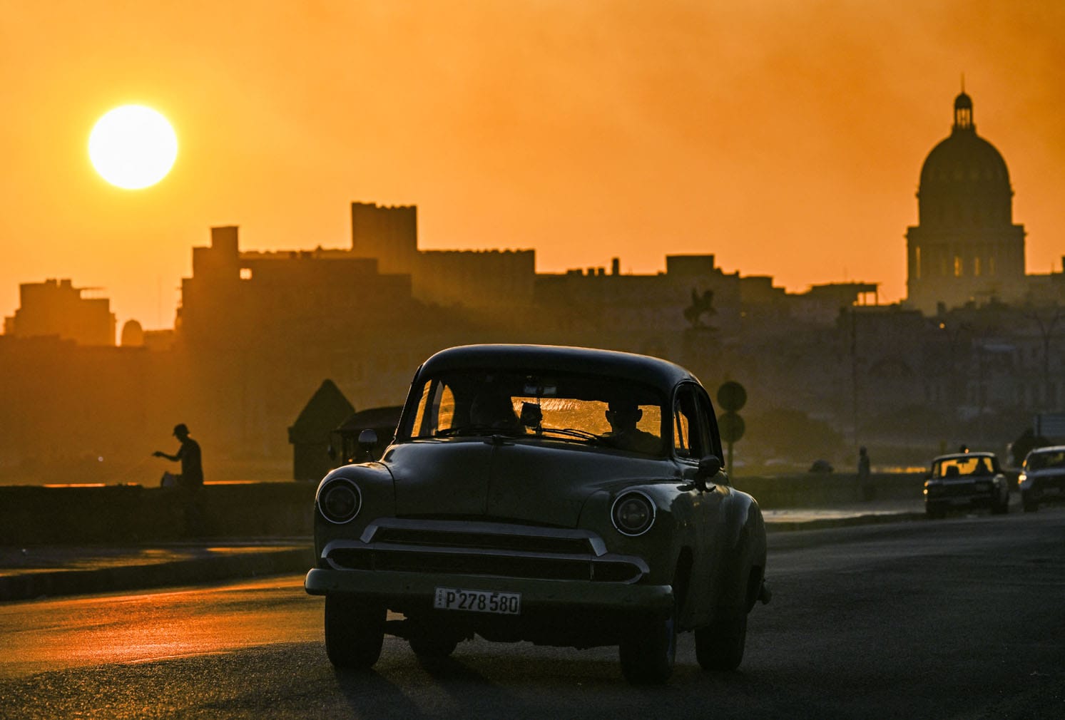 An old car drives along Havana’s Malecon