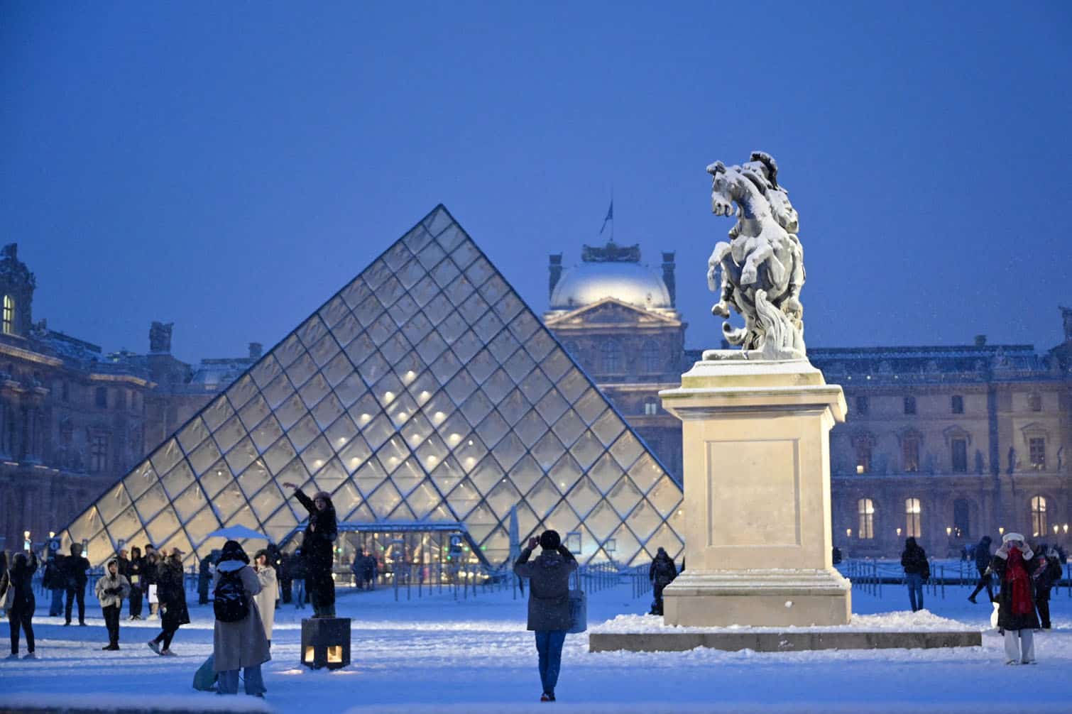 A tourist takes a photo of the Louvre pyramid