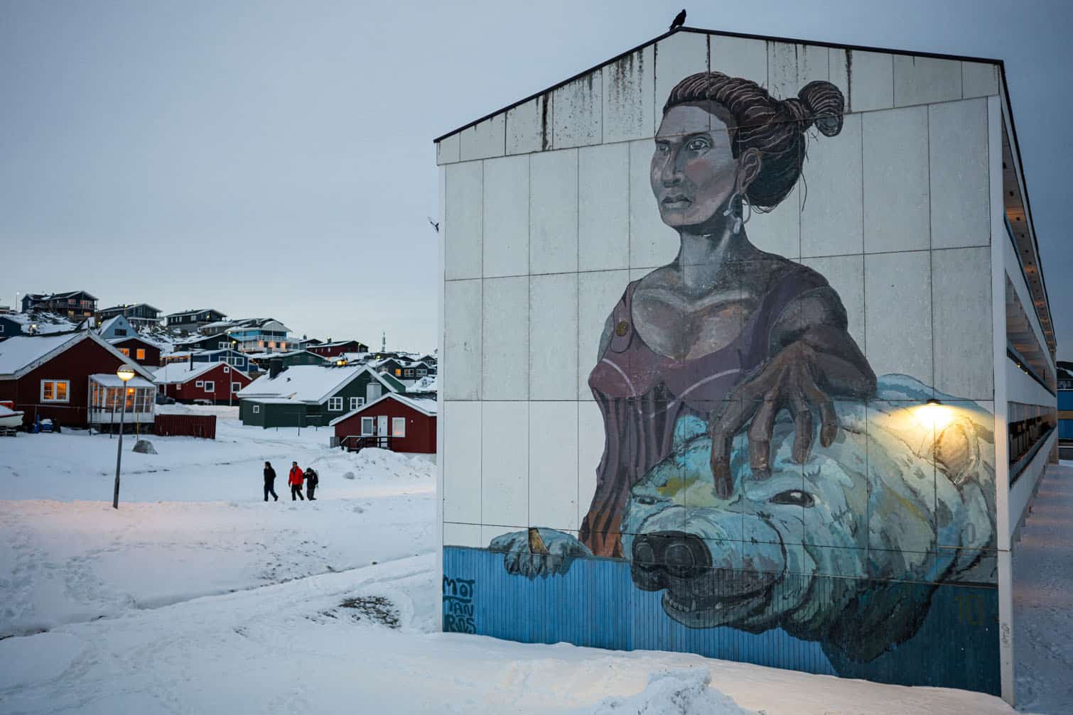 People walk past a large mural depicting a woman and a polar bear