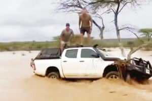 Two men standing on top of a bakkie in floods