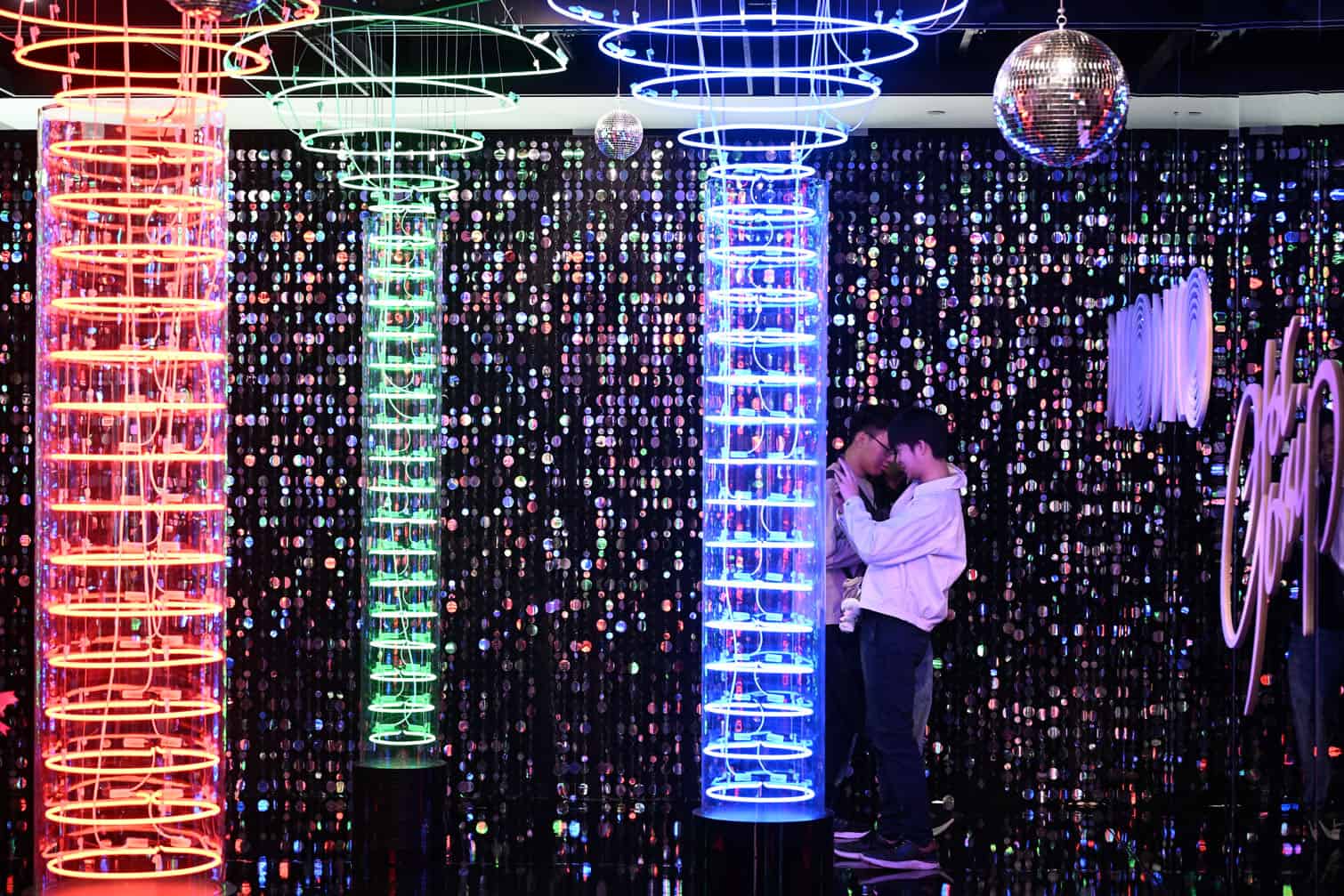 Visitors look at neon signs at the "Luminous Neon" exhibition